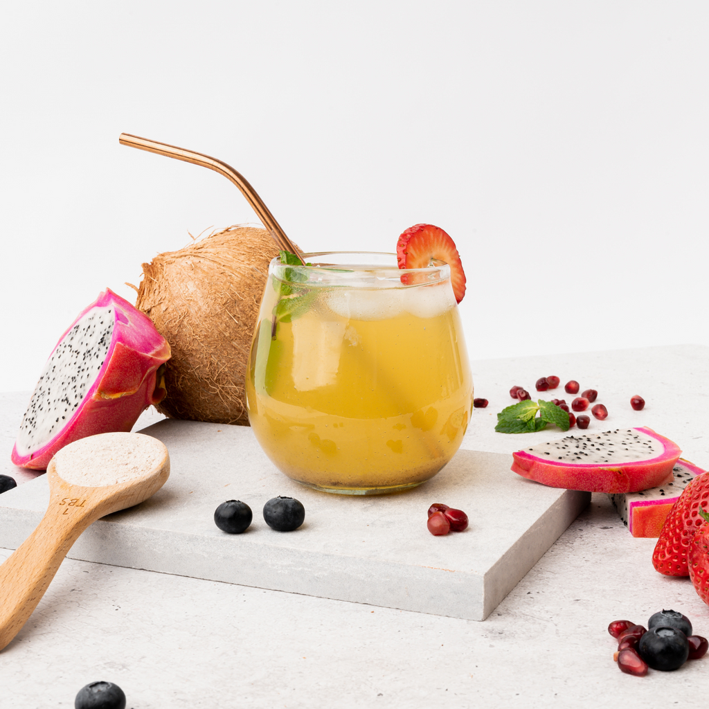 Beauty Infused Collagen drink made in a glass with an eco-friendly straw surrounded by fresh fruit.