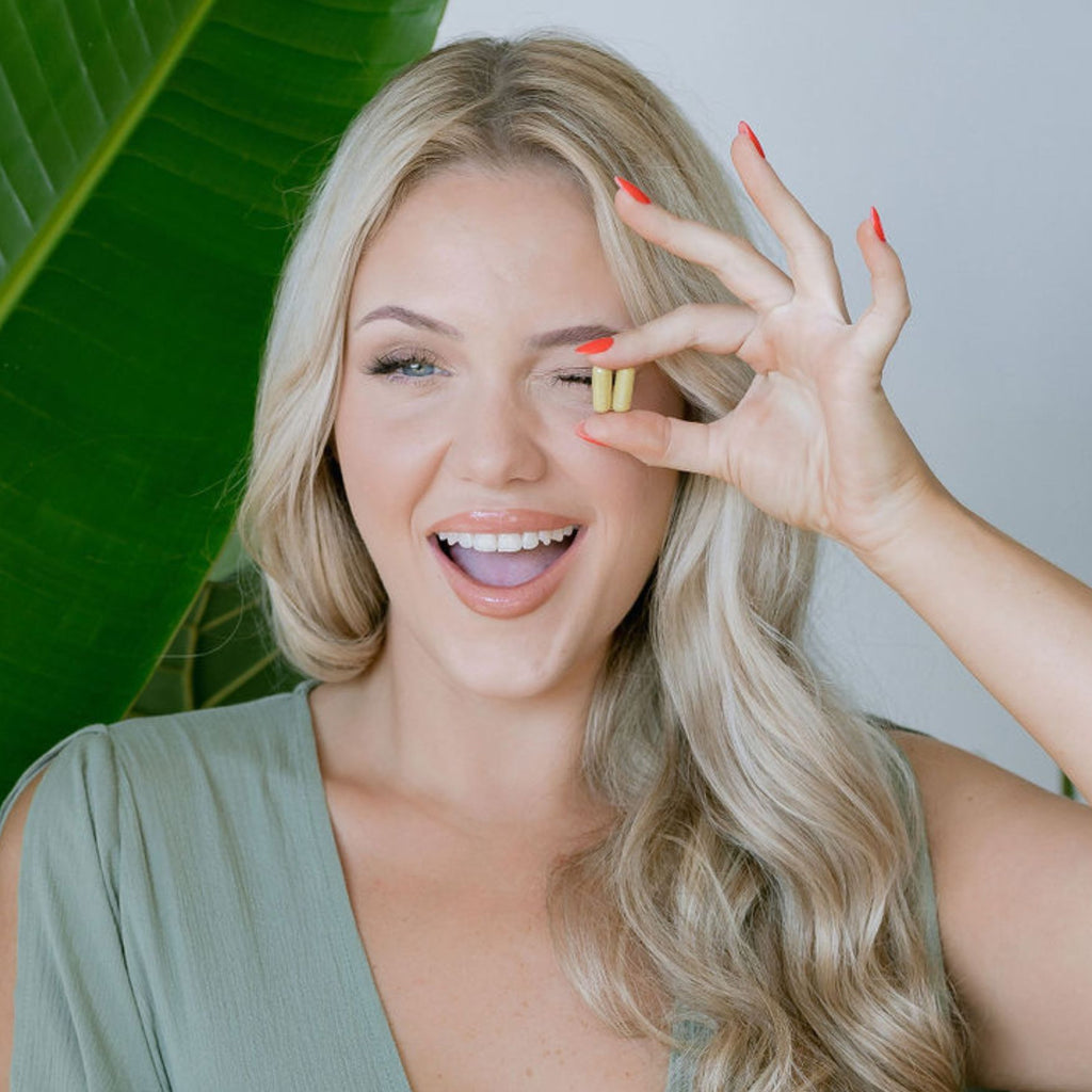 2 Ageless Skin Vitamin Capsules in a happy models hands