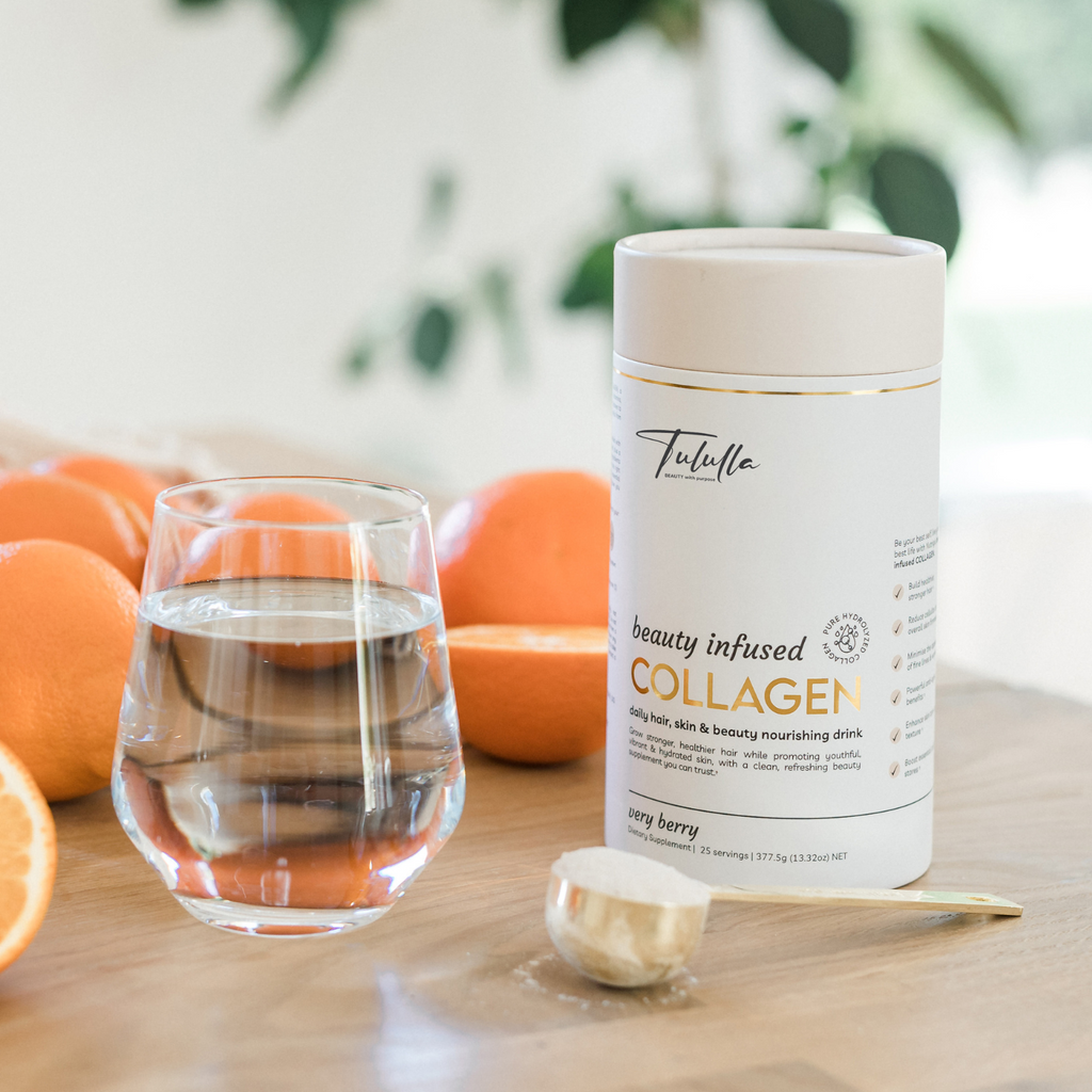 Beauty Infused Collagen packaging next to a scoop of collagen powder and a glass of water